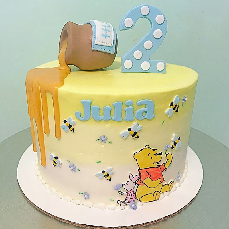 A two-tiered birthday cake decorated with colorful sprinkles and a '2' candle.