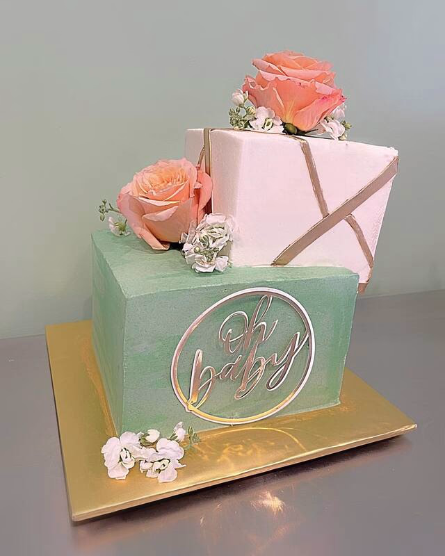 A novelty cake shaped like a gift box with baby-themed decorations.