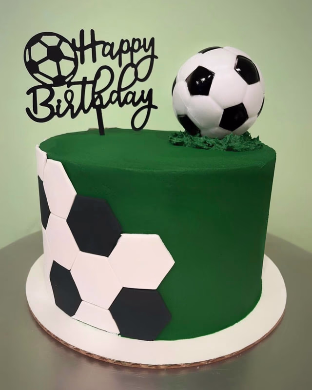 A sporty cake with a soccer theme, possibly shaped like a soccer ball or featuring field markings.