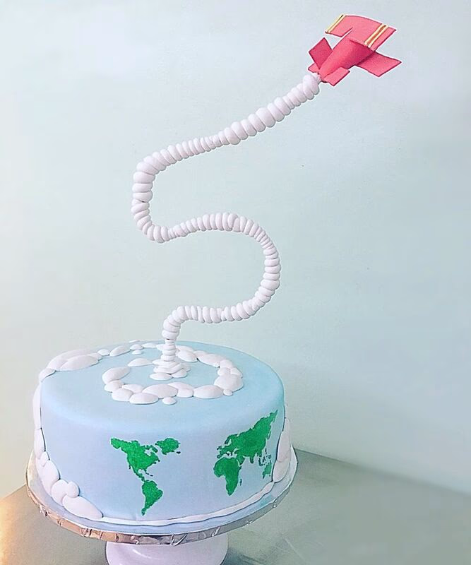 A cake with a travel theme, possibly featuring globes, suitcases, or landmarks.