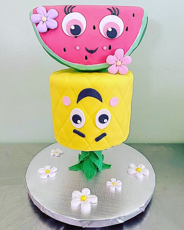 A refreshing cake with a tropical fruit theme, featuring watermelon and pineapple designs.