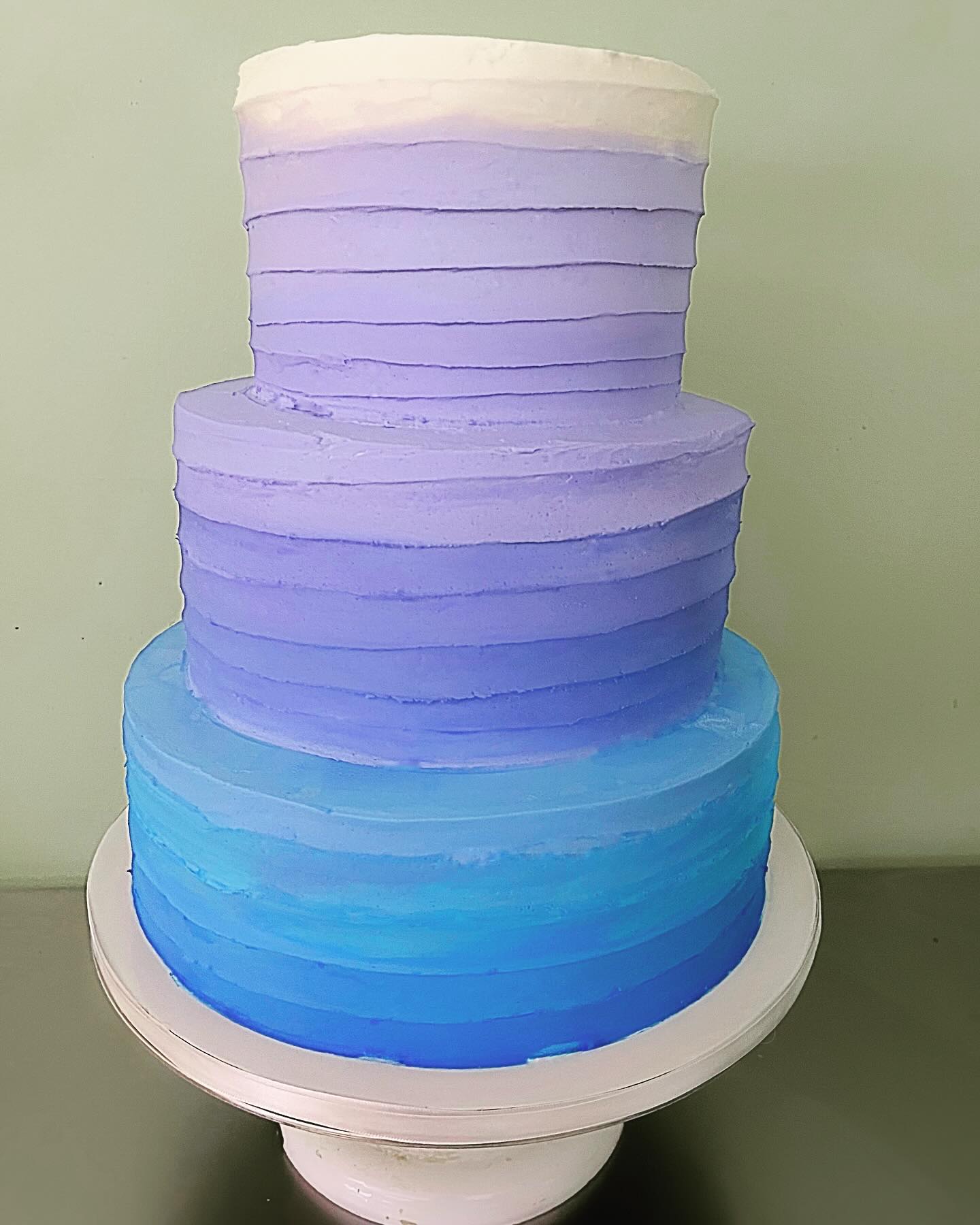A layered cake that features different hues of blue blending into purple.