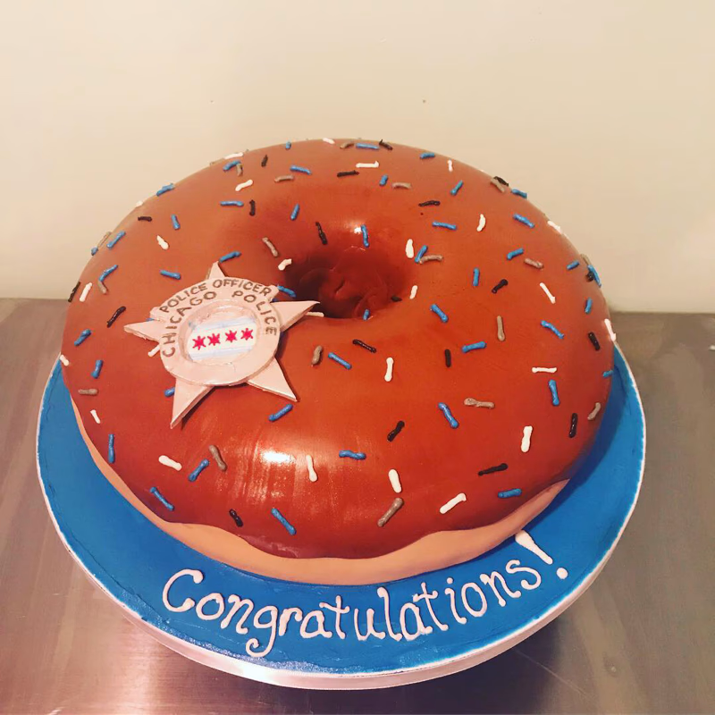 A fun cake designed with a police officer theme, possibly featuring donuts.