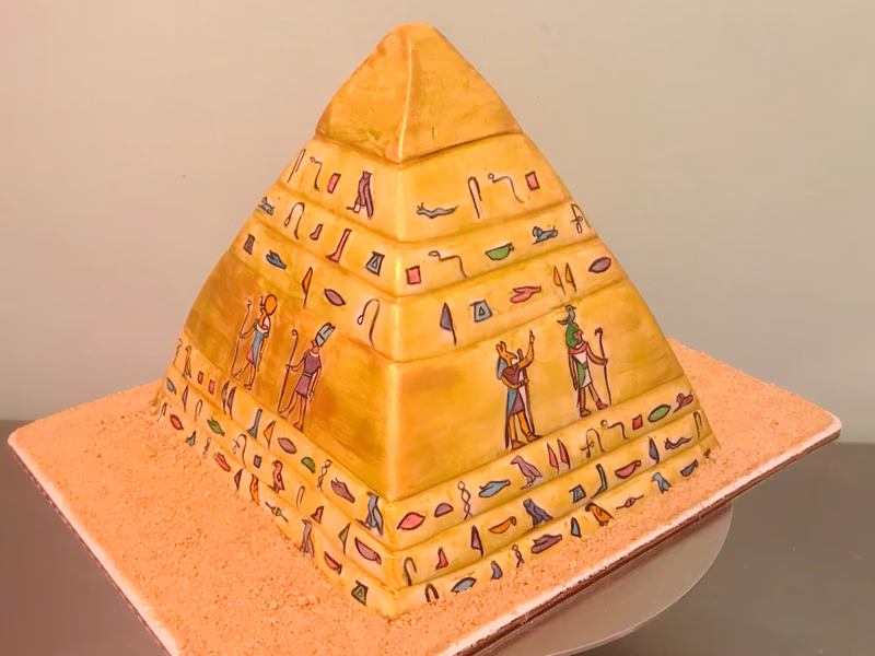 A unique cake shaped like a pyramid, possibly with ancient Egyptian-inspired details.